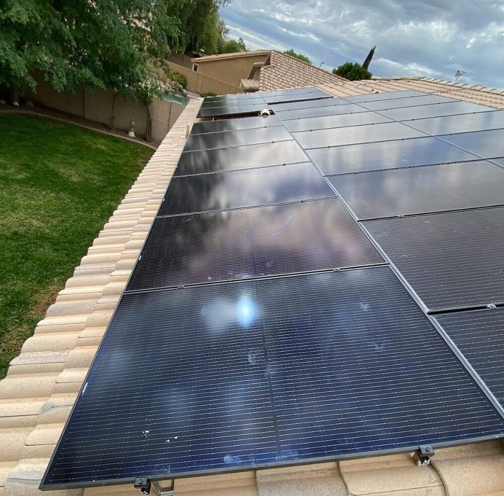 Close-up rooftop solar panels with sky reflection